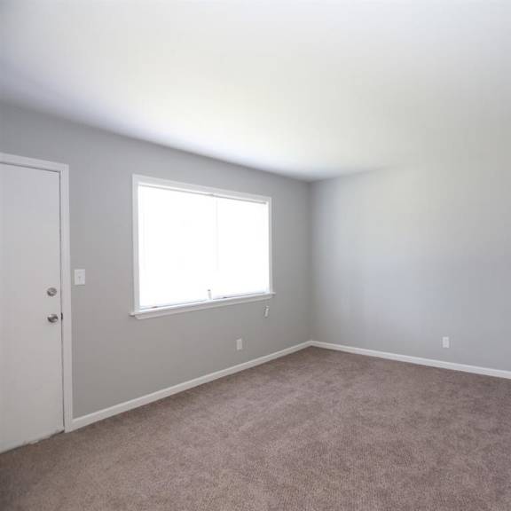 an empty room with a window and carpet