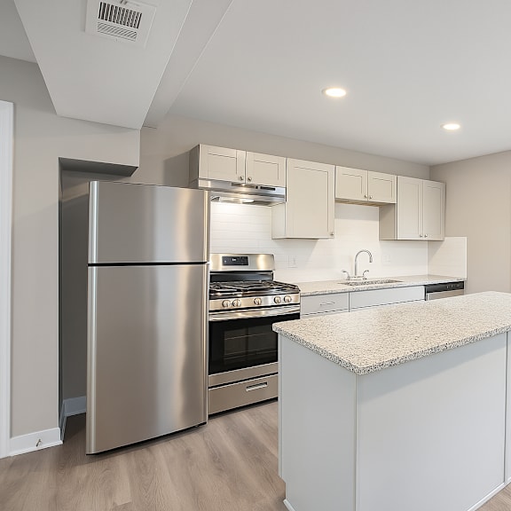 a kitchen with a stainless steel refrigerator and a granite countertop.at palisades apartments, kansas city missouri
