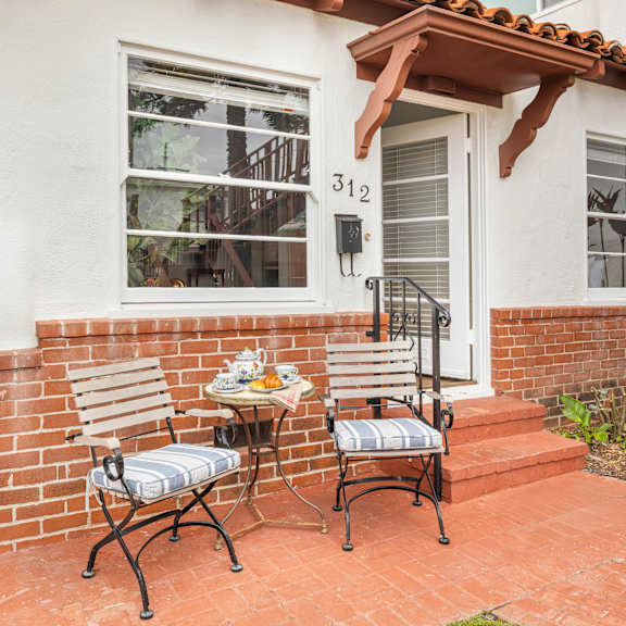 a patio with a table and two chairs in front of a house with the number 312 on it.
