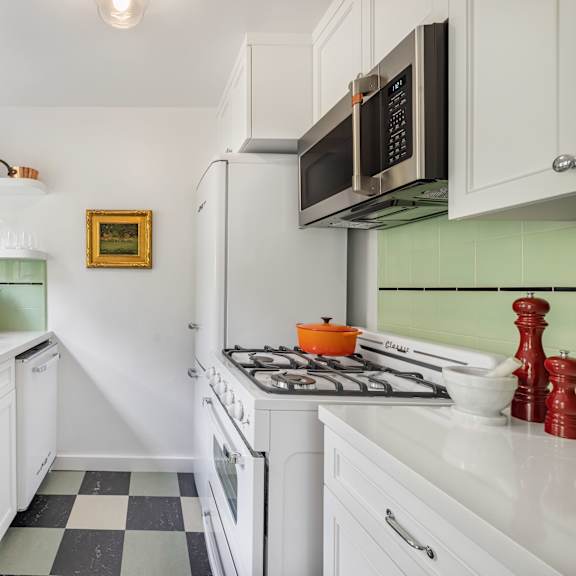a kitchen with white cabinets and a black and white checkered floor.