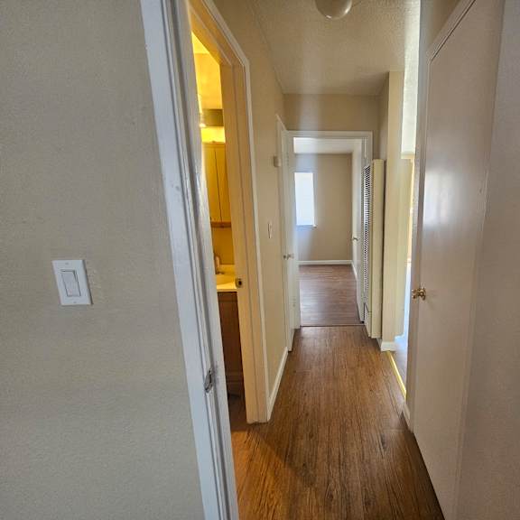 a long hallway with doors on both sides and a light switch on the wall.