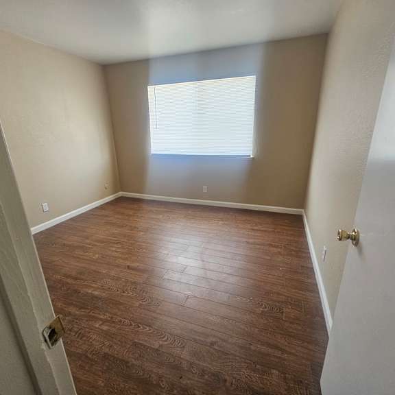 a room with wooden flooring and a window letting in light.
