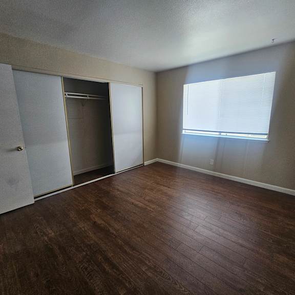 empty room with a brown floor and white walls.