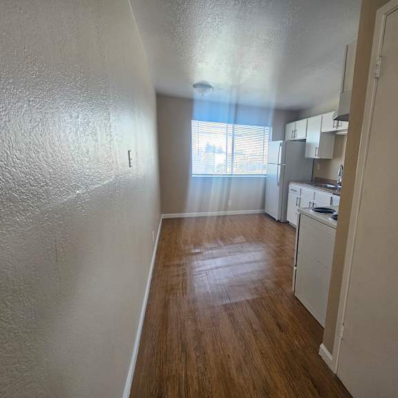 a kitchen area with white cabinets and a wooden floor.