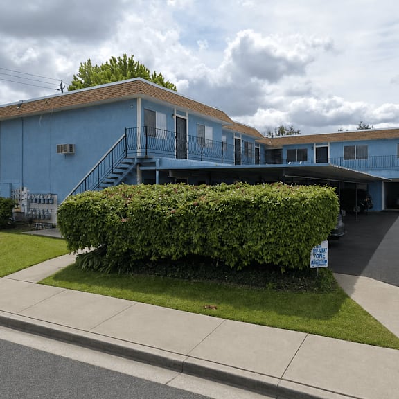 Thumbnail 1 of 13 A blue building with a parking lot in front.