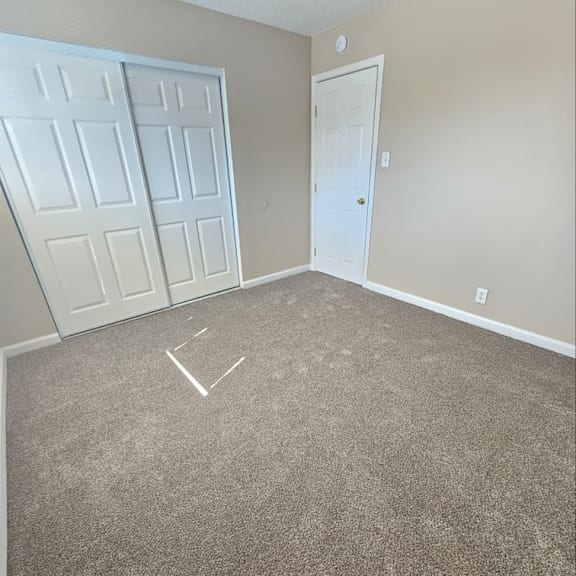 Thumbnail 7 of 14 an empty bedroom with a carpeted floor and two doors
