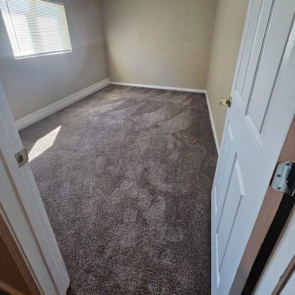 Thumbnail 9 of 14 an empty bedroom with a carpeted floor and a window