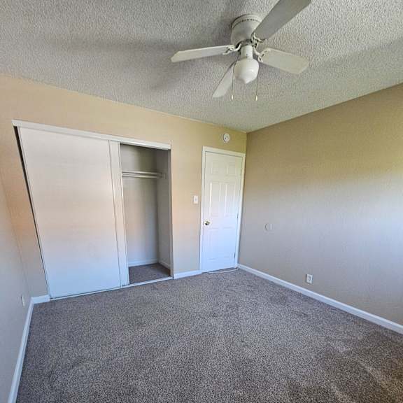 Thumbnail 4 of 14 an empty living room with carpet and a ceiling fan