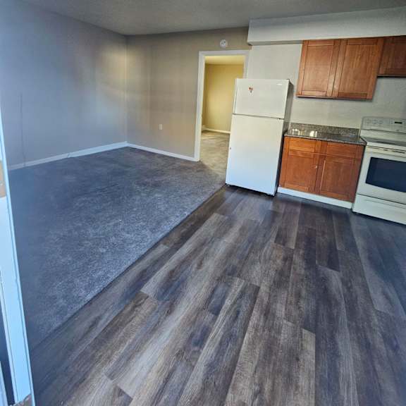 Thumbnail 13 of 14 an empty kitchen and living room with wood floors and white appliances