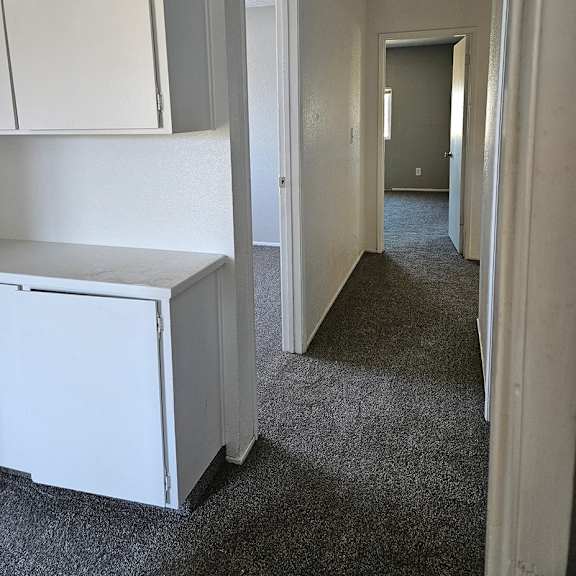 Thumbnail 9 of 12 a hallway with white cabinets and a white refrigerator     and a door