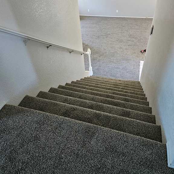 Thumbnail 5 of 12 a view of the stairs from the top of them looking into a carpeted room