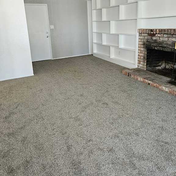 Thumbnail 11 of 12 an empty living room with a fireplace and a carpeted floor