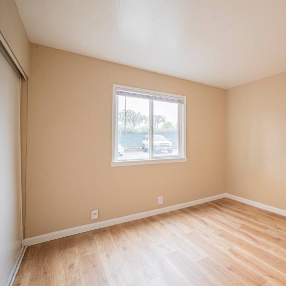 Thumbnail 17 of 18 Empty room with a window and wooden flooring.