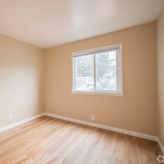 Thumbnail 5 of 18 A room with a window and wooden flooring.