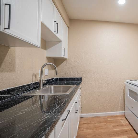 Thumbnail 16 of 18 A kitchen with a white refrigerator, sink, and cabinets.