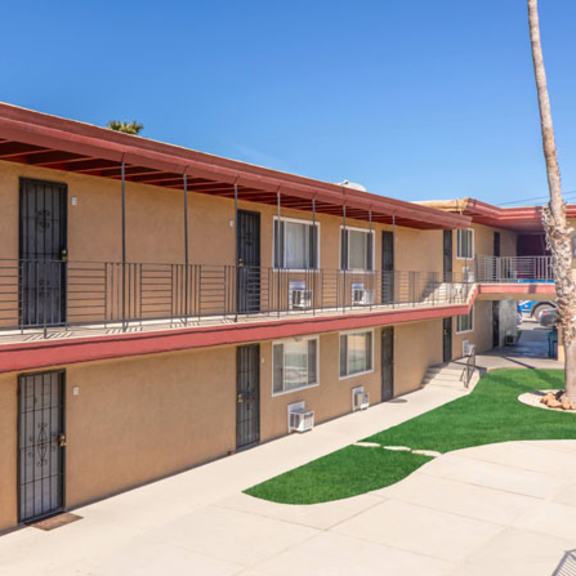Thumbnail 11 of 19 A row of apartment buildings with balconies and a palm tree in the front yard.