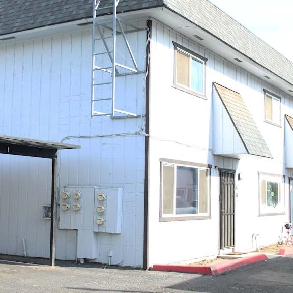 a white building with a grey roof and a ladder on the side.