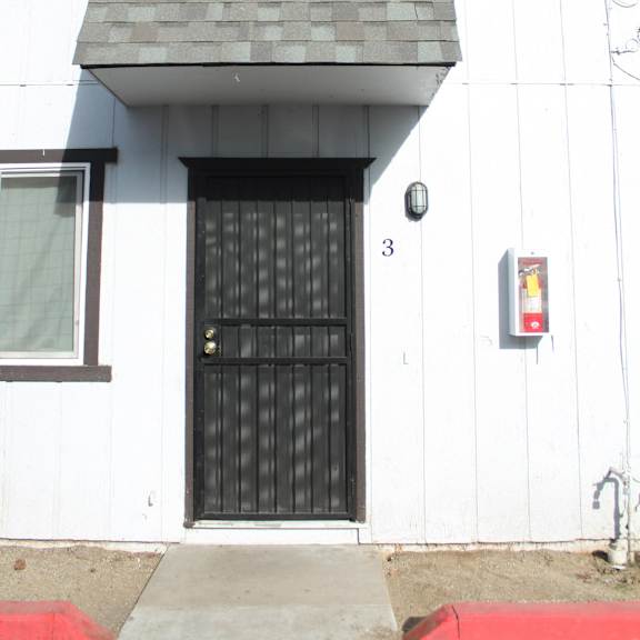 a black door with a gold handle is on a white house.
