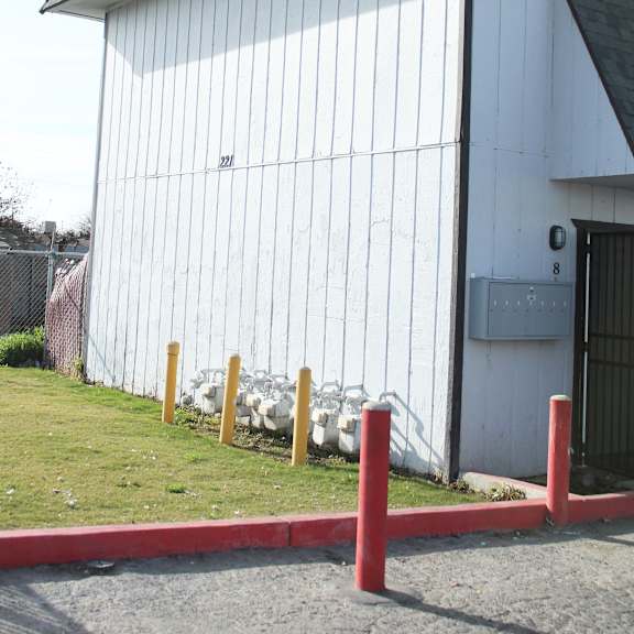 a white building with a black roof and a red fence in front.