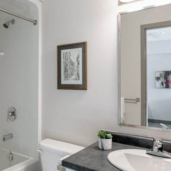 a bathroom with a white tub, sink, and a picture on the wall.