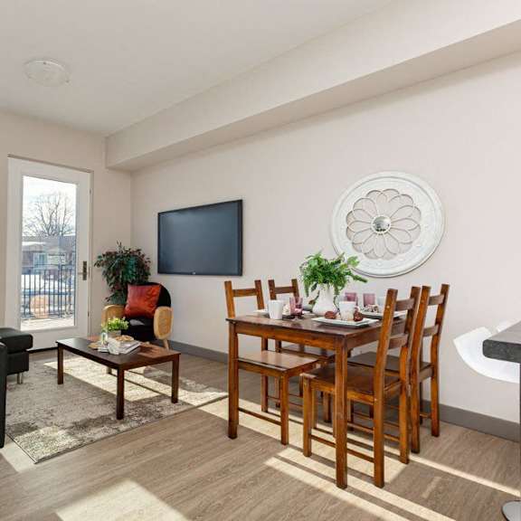 a living room with a black couch, a wooden dining table, and a television.