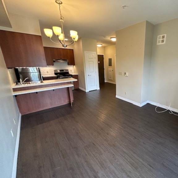 a kitchen with dark wood floors and a white wall.