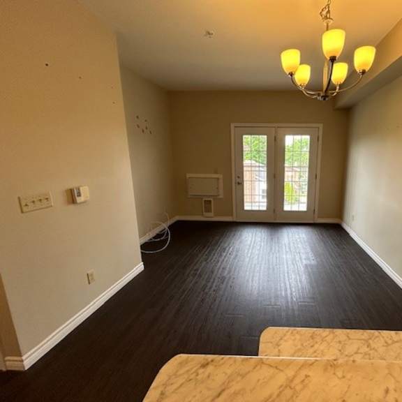 a room with a chandelier, a window, and a door leading outside.