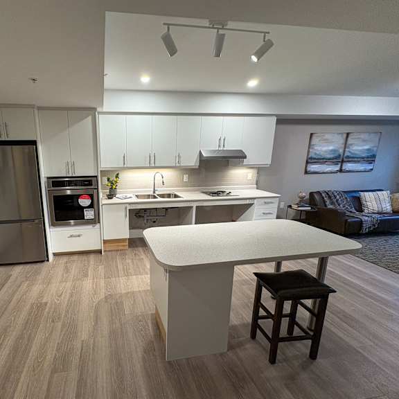 a modern kitchen with a white island and wooden flooring.