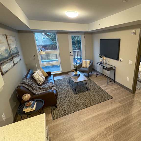 a living room with a brown couch and a television on the wall.