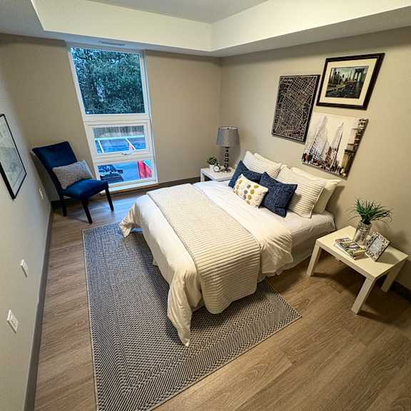 a bedroom with a bed, chair, and pictures on the wall.