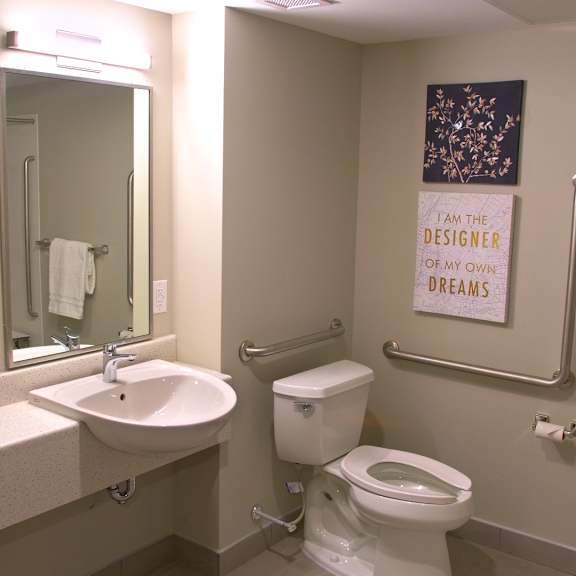 a bathroom with a toilet, sink, mirror and a sign on the wall.