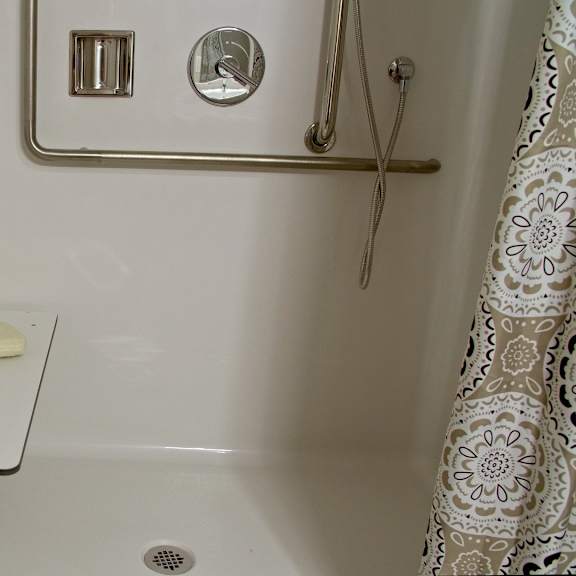 a white bathroom with a white tub and a white towel hanging on the door.