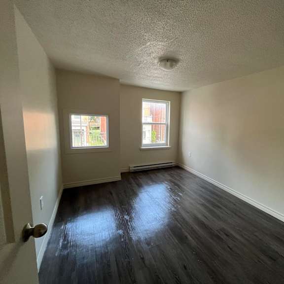 a room with a wooden floor and two windows.