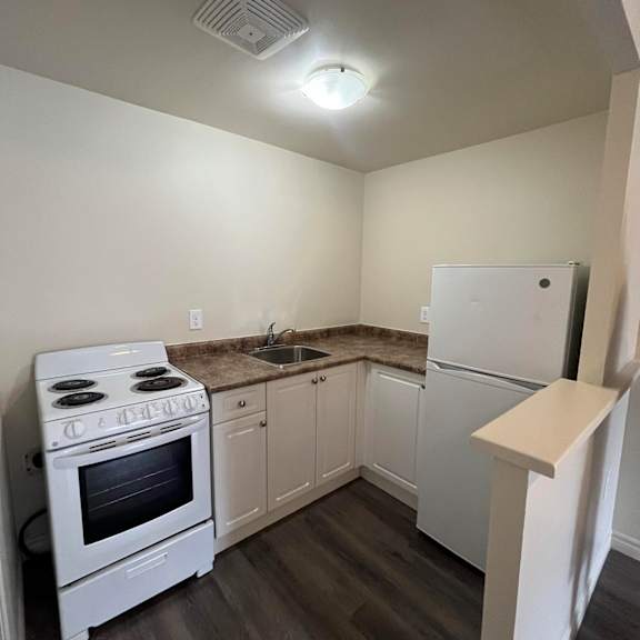 a white stove and refrigerator in a kitchen with wood floors.