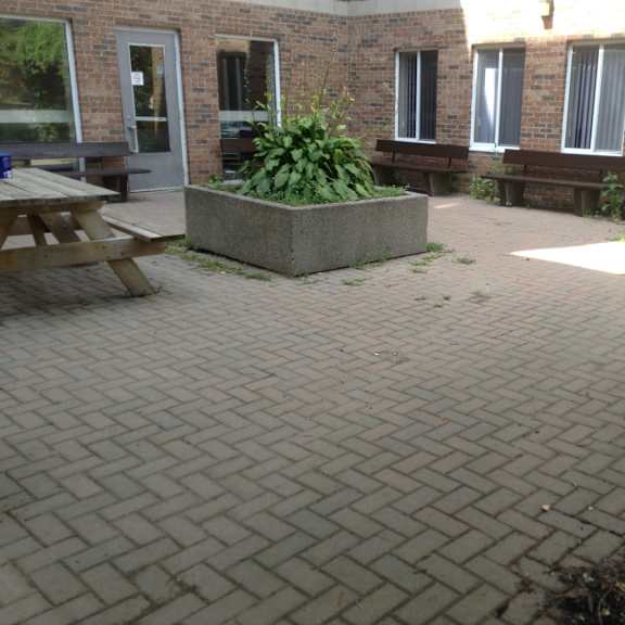 a patio with a table and benches outside a brick building.