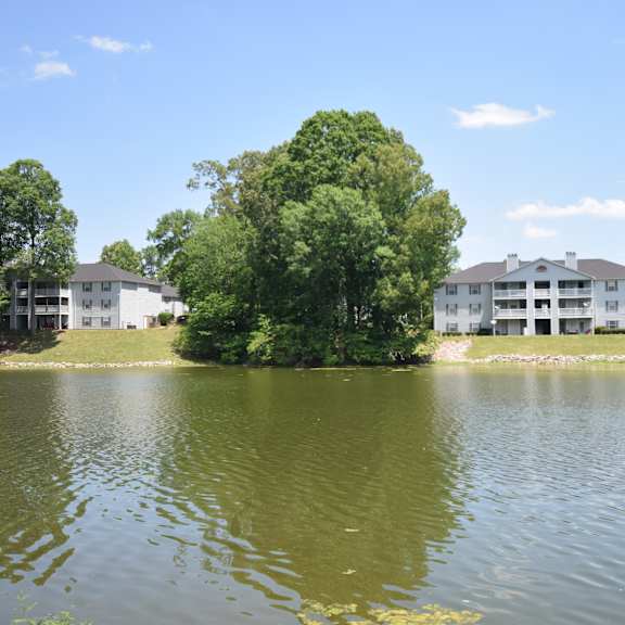 a large white building sits on the edge of a lake surrounded by trees.