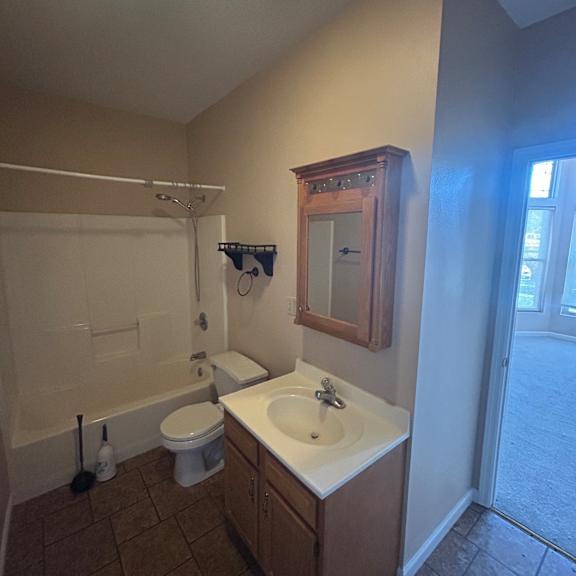 a bathroom with a toilet, sink, and shower.