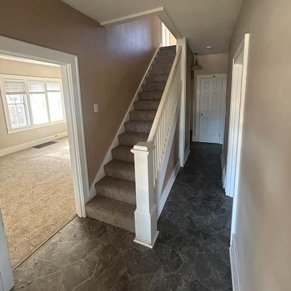 a staircase with a marble wall on the side and a window at the bottom.