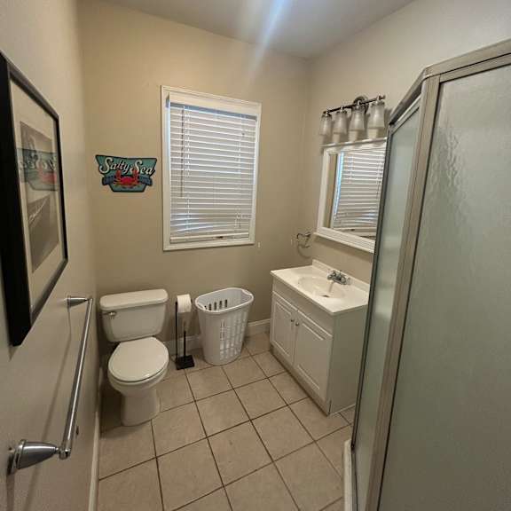 a bathroom with a light on the ceiling, a window with blinds, a towel dispenser, and a picture frame on the counter.