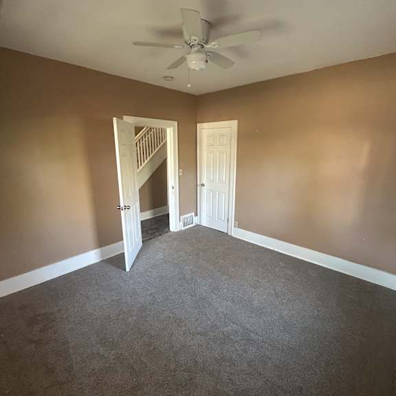 a ceiling fan is mounted on a wall above a vent.