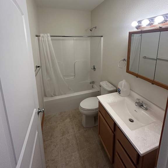 a white bathroom with a toilet, sink, and shower.