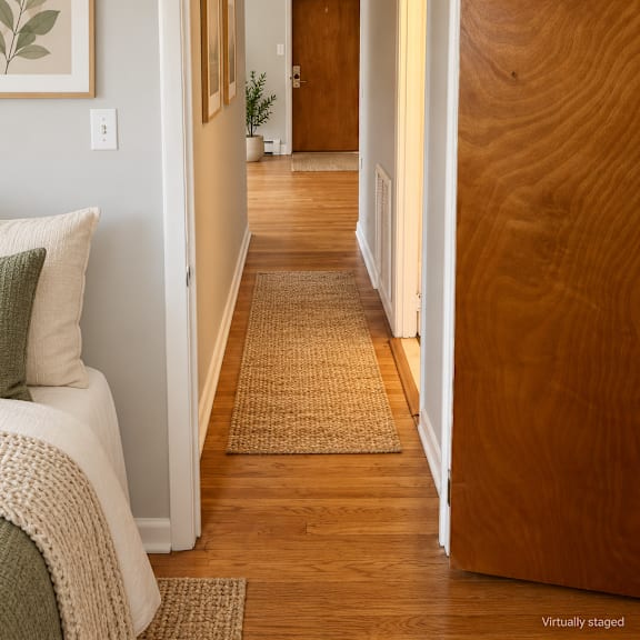 a hallway with a brown door and a rug on the floor.