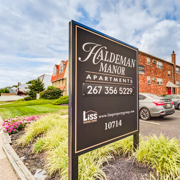 a sign for haldeman manor apartments is displayed in front of a brick building.