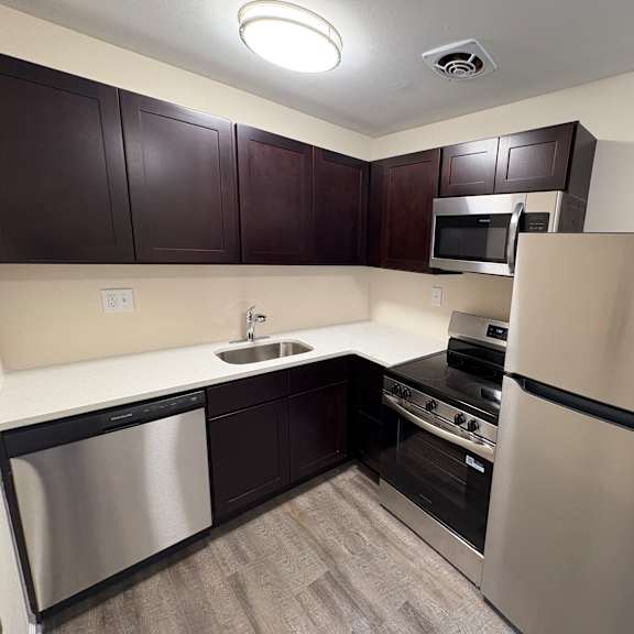 a modern kitchen with dark brown cabinets and stainless steel appliances.