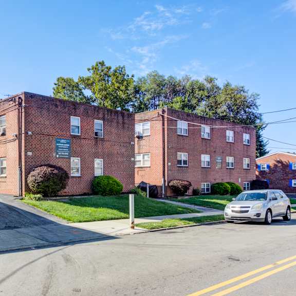 a street view of a residential area with apartment buildings and a car parked on the side of the road.