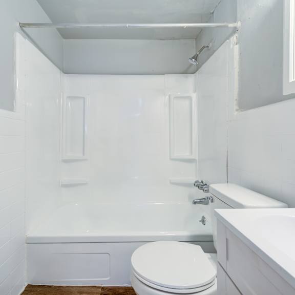a white bathroom with a toilet, tub, and sink.