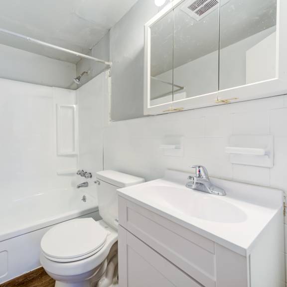 a white bathroom with a toilet, sink, and mirror.