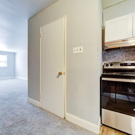 a kitchen with a stove and oven in a room with carpet.