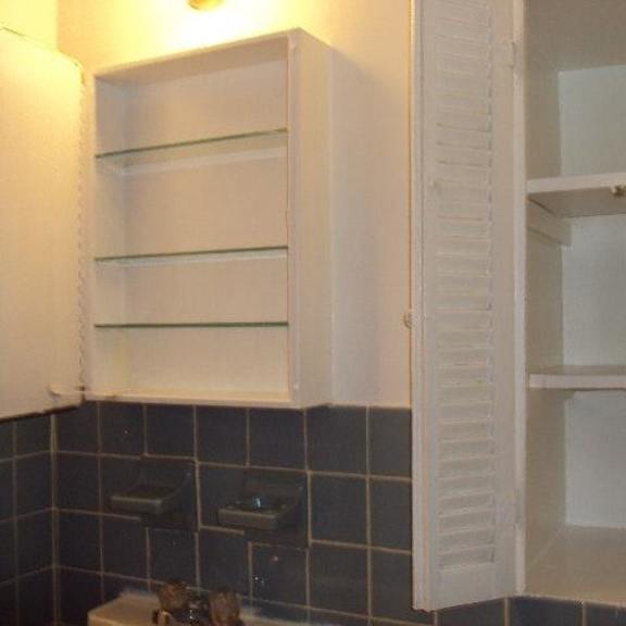 a bathroom with an open cabinet in the corner