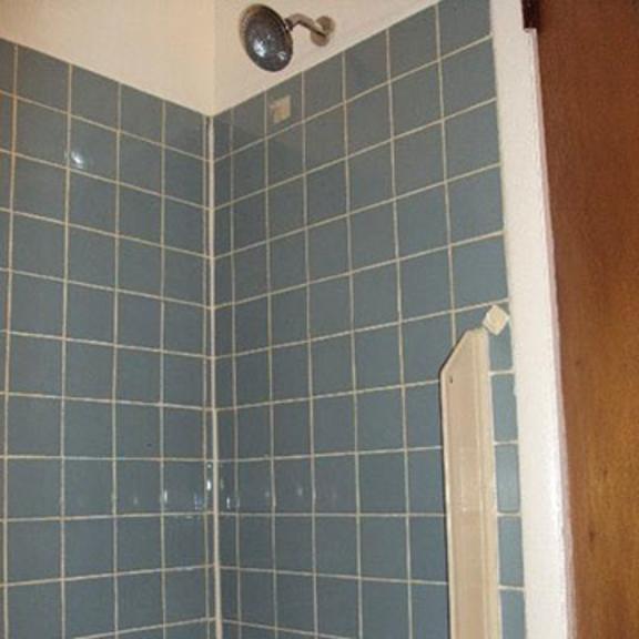 a blue tiled bathroom with a shower and a sink